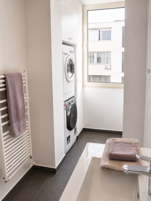 Modern laundry room with stacked washer-dryer, towel rack, and folded linens at Pascale Beaud hotel in Cannes