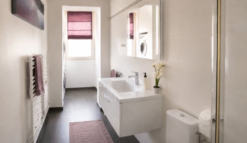 Modern bathroom in Cannes vacation rental with white vanity, sink, toilet, and laundry room access