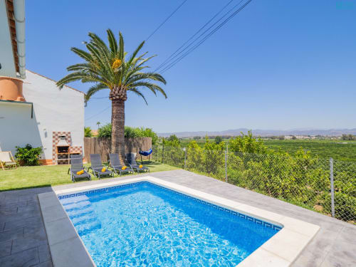 Villa Riad de Maruchi en Alhaurín de la Torre con piscina azul, palmera, tumbonas y vistas al campo