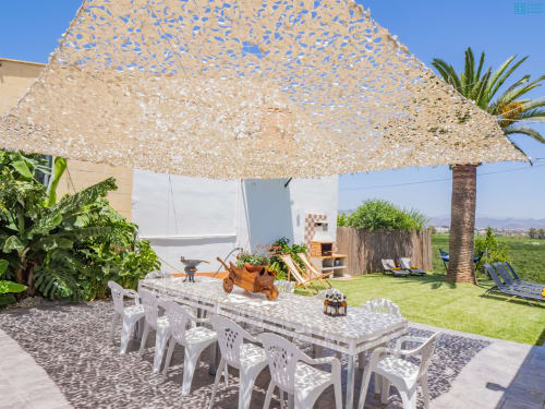 Patio exterior de la villa Alhaurín Loft con mesa de comedor, toldo de sombra, tumbonas y jardines verdes con vistas a la montaña