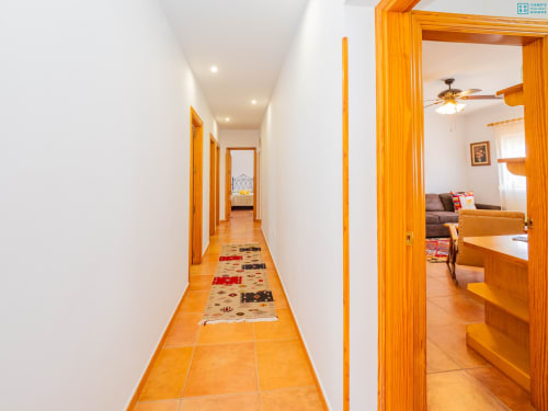 Pasillo luminoso con suelos de baldosas de terracota y marcos de puertas de madera en la villa Alhaurín Loft City Center, conducente a las habitaciones de huéspedes