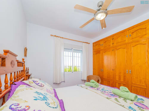 Dormitorio luminoso en la villa Riad de Maruchi con camas gemelas, armario de madera, ventilador de techo y vistas al jardín
