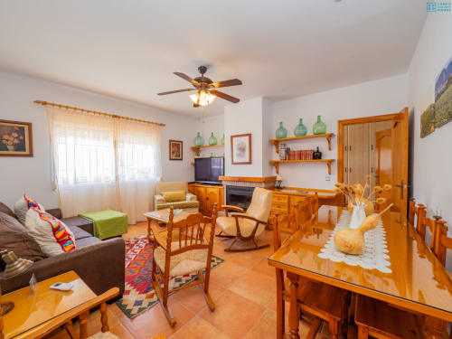 Amplio salón con muebles de madera, pisos de terracota, chimenea y comedor en la villa Alhaurín Loft City Center
