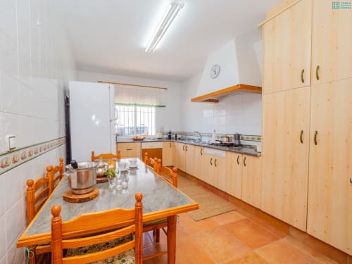 Amplia cocina con muebles de madera, mesa de comedor y electrodomésticos modernos en la villa Riad de Maruchi en Alhaurín de la Torre