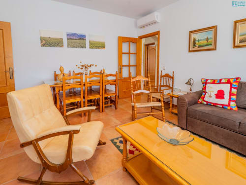Amplio salón de la villa Riad de Maruchi con muebles de madera, butaca color crema, pisos de barro y comodidades modernas