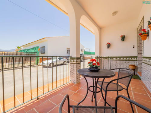 Terraza soleada con mesa redonda, sillas y flores en maceta en la villa Alhaurín Loft City Center en España