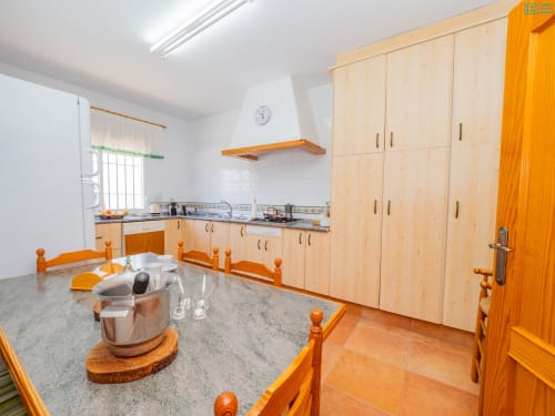 Amplia cocina y comedor en la villa Riad de Maruchi con gabinetes de madera clara, encimeras de mármol y madera naranja