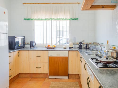 Cocina luminosa con gabinetes de madera, electrodomésticos de acero inoxidable y amplia ventana en la villa Alhaurín Loft