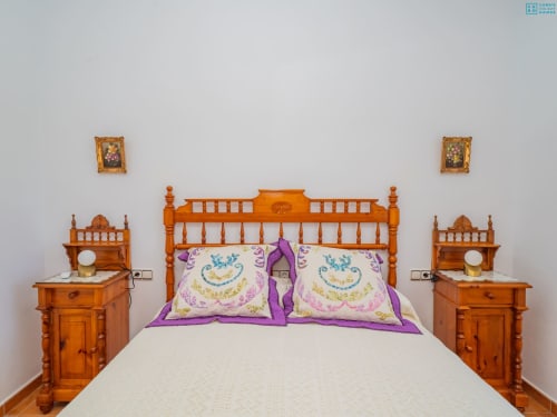Dormitorio en Alhaurín Loft Centro con cama de madera, almohadas moradas y mesitas de noche a juego
