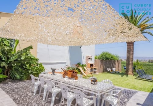 Terraza exterior de la villa Riad de Maruchi con zona sombreada, mesa de comedor y vistas a la montaña en Alhaurín de la Torre.