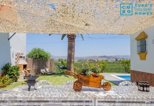 Terraza de la villa Riad de Maruchi con palmera, tumbonas, maceta de madera, vistas a la piscina y paisaje rural de Alhaurín