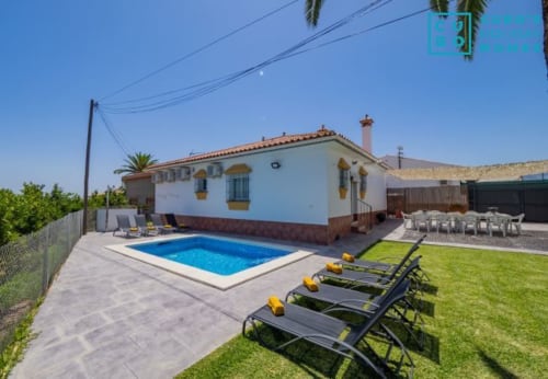 Villa Riad de Maruchi en Alhaurín de la Torre con piscina azul, tumbonas, césped cuidado y edificio encalado