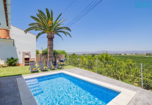 Terraza con piscina de la villa Riad de Maruchi en Alhaurín de la Torre con palmera, tumbonas y vistas al campo