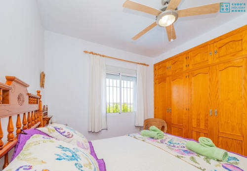 Dormitorio luminoso con camas gemelas, armarios de madera, ventilador de techo y balcón con vistas a la piscina en Alhaurín Loft