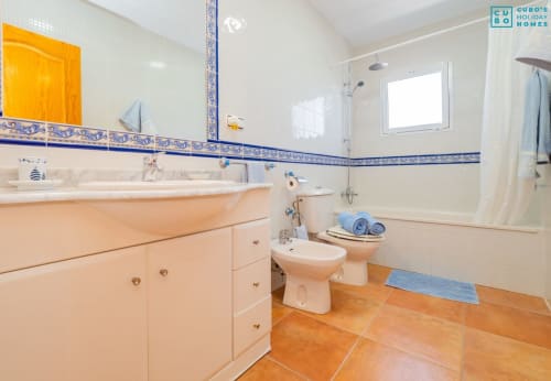 Baño moderno con tocador melocotón, azulejos azules y blancos, inodoro, bidé y ducha en villa de Alhaurín
