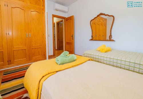 Dormitorio luminoso con dos camas, armario de madera y ropa de cama colorida en la villa Alhaurín Loft City Center en España
