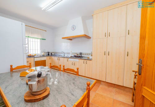 Cocina moderna en villa de Alhaurín con armarios de madera clara, detalles naranjas, electrodomésticos de acero inoxidable y mesa de comedor