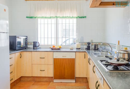 Cocina luminosa en villa Alhaurín Loft con muebles de madera clara, electrodomésticos de acero inoxidable y vistas al jardín