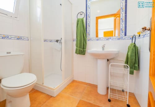 Baño de Alhaurín Loft con azulejos blancos, molduras naranjas, toallas verdes, lavabo pedestal, inodoro y cabina de ducha