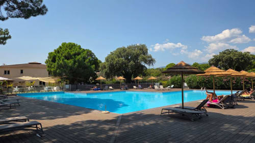 Piscine bleu éclatant avec transats et parasols à l'hôtel Tamaricciu Di Cala Rossa à Lecci, Corse