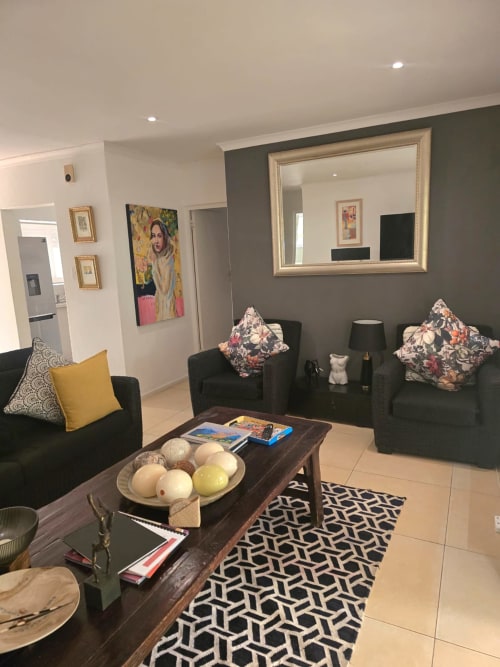 Modern living room in Art House apartment, Stellenbosch with black seating, patterned pillows, and decorative artwork