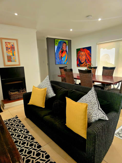 Modern Art House living area in Stellenbosch with black sofa, yellow pillows, fireplace, and vibrant artwork on walls