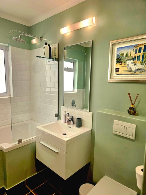Modern bathroom with green walls, white subway tile shower, floating vanity, and mirror in Art House apartment, Stellenbosch