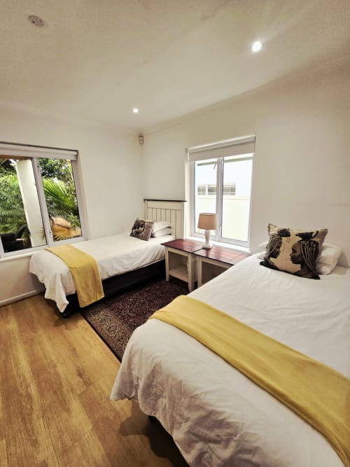 Twin bedroom with yellow accents, wooden floors, and garden views at Art House guesthouse in Stellenbosch