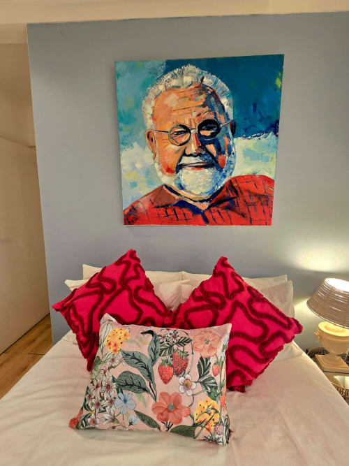Colorful portrait painting above bed with red patterned pillows and floral cushion in Stellenbosch Art House apartment