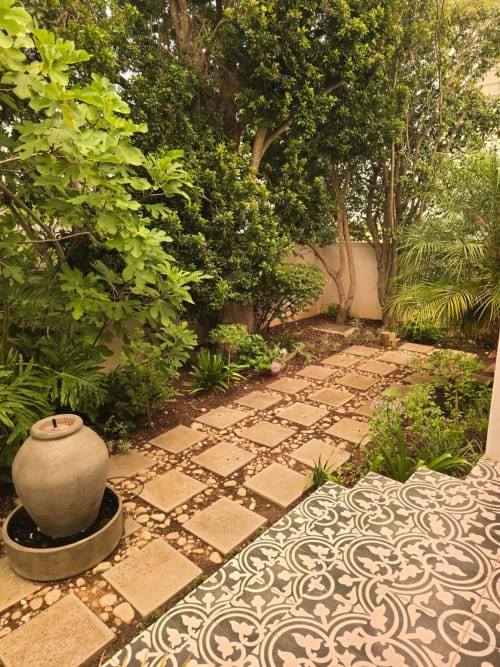 Lush garden courtyard in Stellenbosch with stone pathway, decorative tiles, and tall trees leading to the Art House apartment
