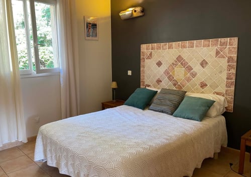 Spacieuse chambre de Vista D'oro à Monacia d'Aullène avec tête de lit carrelée, vue mer, oreillers verts et design moderne