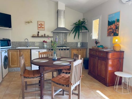 Cuisine-salle à manger Vista D'oro à Monacia d'Aullène avec mobilier en bois, plans de travail en granit et affiche vue mer