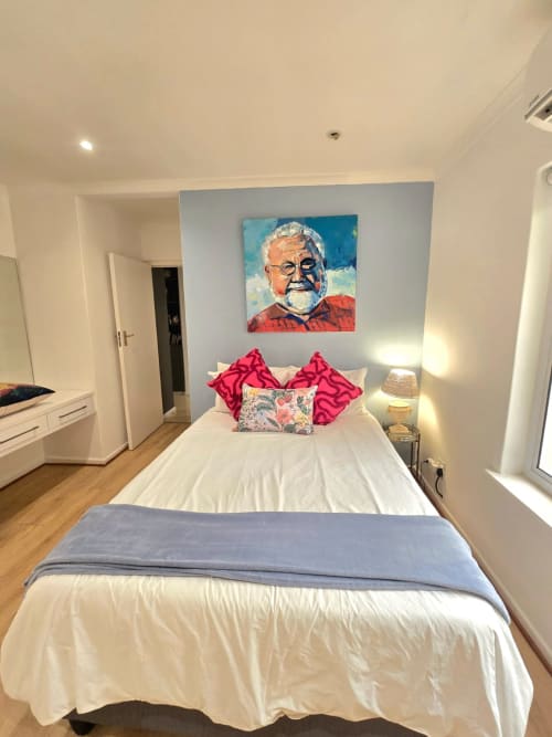 Modern bedroom in Stellenbosch Art House with white bed, pink pillows, colorful portrait artwork, and mountain views