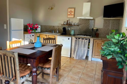 Cuisine moderne et salle à manger à Vista D'oro à Monacia d'Aullène avec appareils électroménagers, table en bois et vue sur mer.