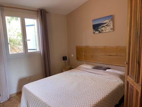 Chambre moderne avec tête de lit en bois, literie blanche et œuvre d'art marine à l'hôtel Vista D'oro en Corse