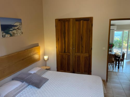 Chambre spacieuse à Vista D'oro à Monacia d'Aullène avec lit en bois, vue sur la mer, armoire et accès à la salle à manger