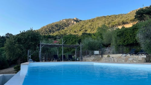 Piscine de l'hôtel Vista D'oro avec pergola, transats et versants boisés à Monacia d'Aullène