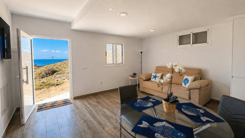 Luminoso salón con vistas al mar, sofá beige, mobiliario moderno y puerta corredera hacia patio con vistas al océano en La Aldea, España
