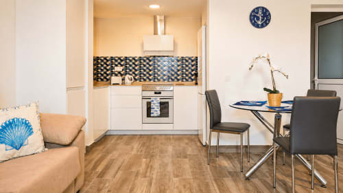 Apartamento moderno de planta abierta en La Aldea con sala, cocina blanca con azulejos decorativos, mesa comedor