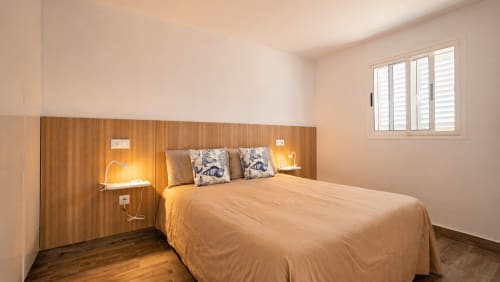 Dormitorio moderno en Apartamento Severo 2, Playa de La Aldea con cabecero de madera, ventana con vista al mar e iluminación cálida
