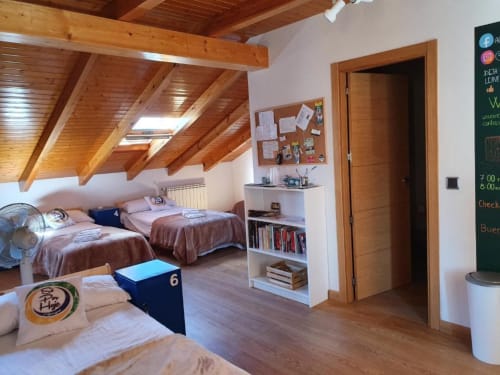 Acogedora habitación compartida en el albergue Só Por Hoje de Astorga con dos camas, vigas de madera e instalaciones compartidas