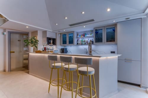 Modern hotel bar at Hôtel De La Fontaine in Nice with marble countertop, brass bar stools, and ambient lighting