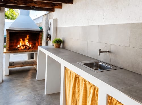 Cocina exterior de la casa rural La Caseta de Ròtova con chimenea de leña, fregadero y vistas a las montañas