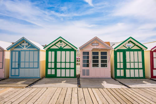 Cabines de plage colorées aux façades verte, bleue et rose sur la promenade en bois de l'hôtel Hidden Bay, France