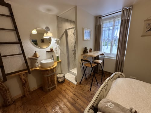 Cozy bedroom at Chambre d'Hôtes Les Iris with wooden desk, en-suite bathroom, and garden views through large windows