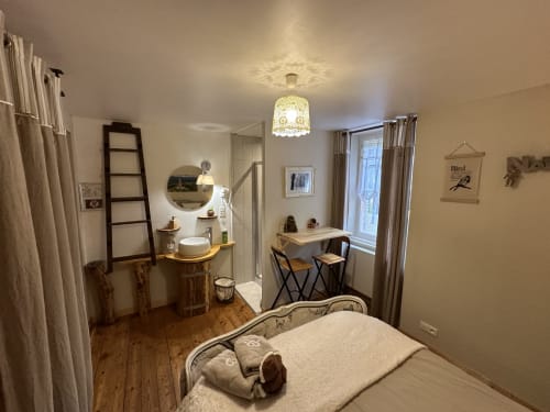 Cozy bedroom at Chambre d'Hôtes Les Iris with bed, vanity, desk, and garden view windows
