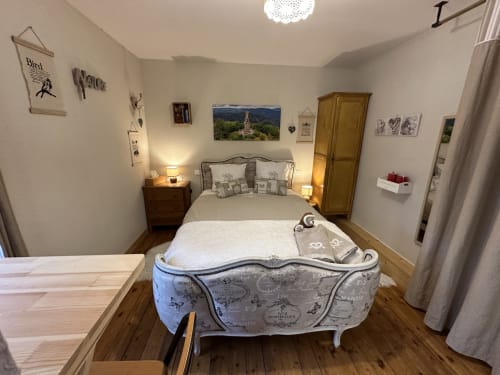 Chambre accueillante aux Iris avec lit orné, tables de nuit en bois, lampes et décoration thématique jardin