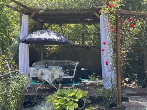 Pergola charmante du gîte Les Iris aux Trois-Épis avec parasol, table de repas et fleurs en fleurs