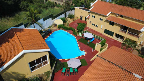 Vista aérea das casarões do Equador em São Tomé com piscina azul brilhante, casarões amarelos com telhados de terracota, vermelho