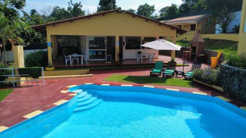 Piscina azul com degraus amarelos na Pousada Casa Amarela em São Tomé, Equador, rodeada por pátio de terracota